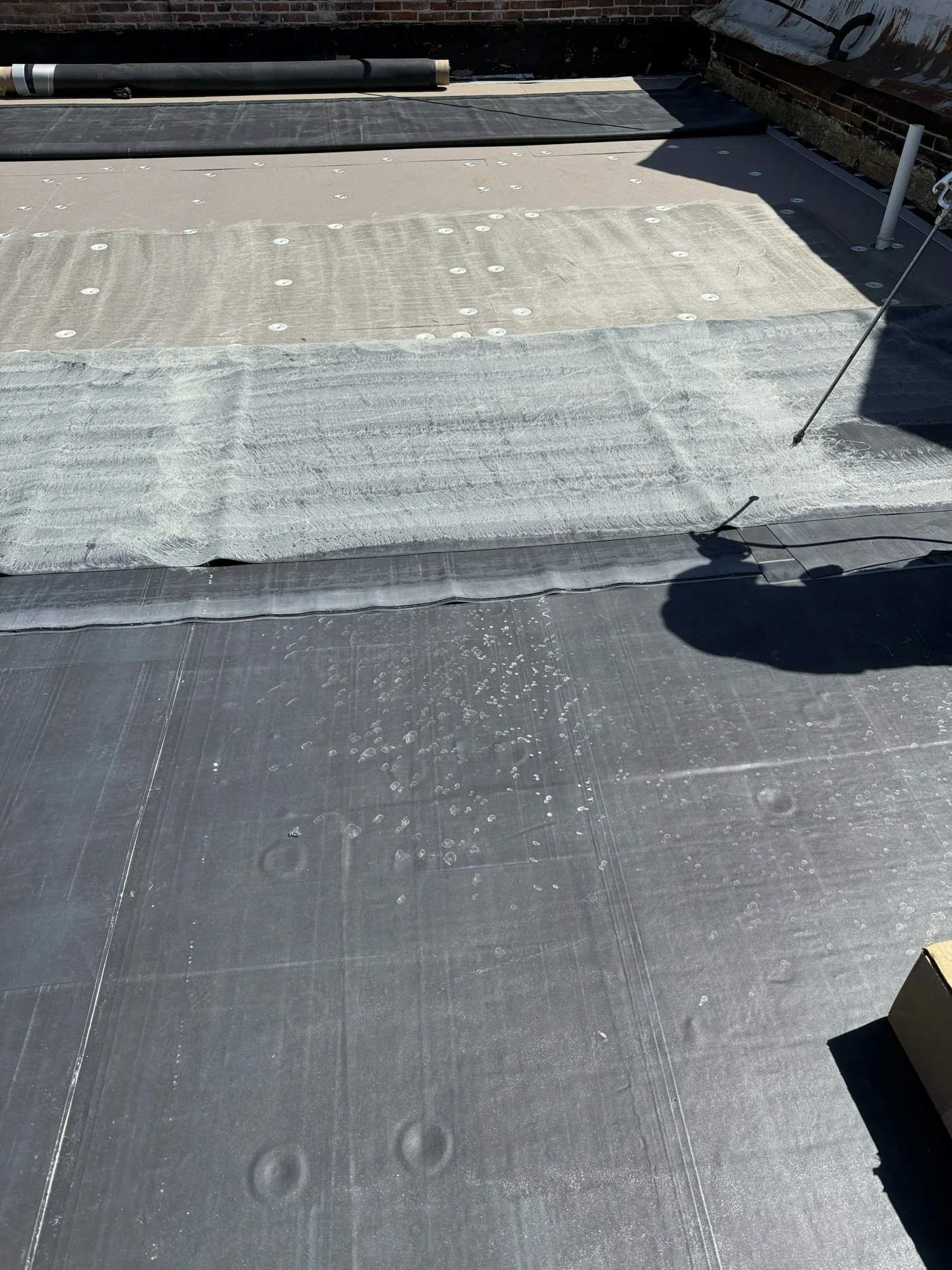 Applying adhesive on roofing membrane